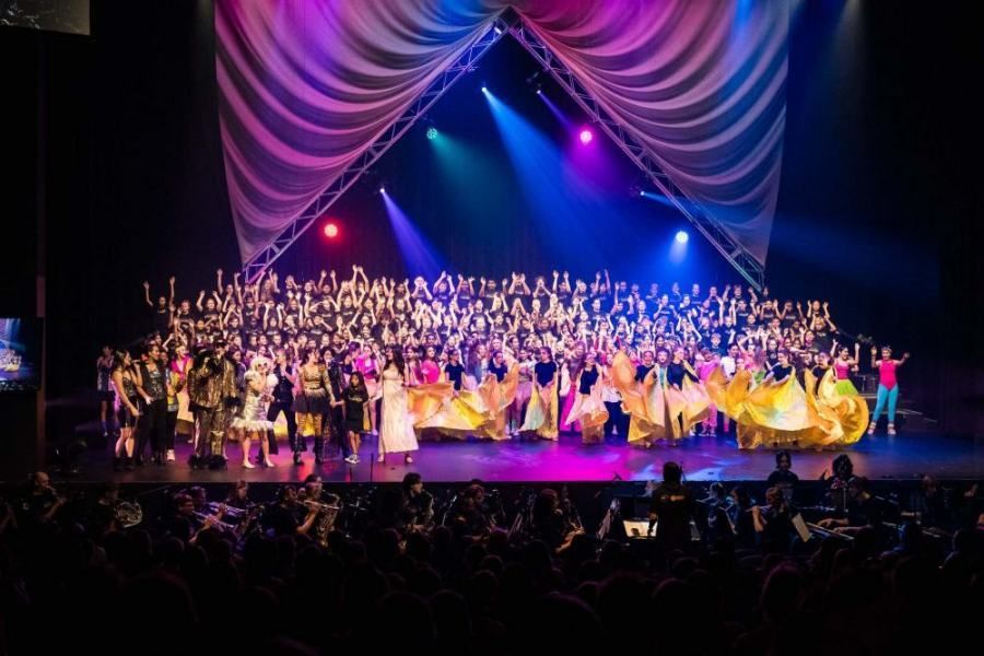A large group of people are standing on a stage in front of a crowd.