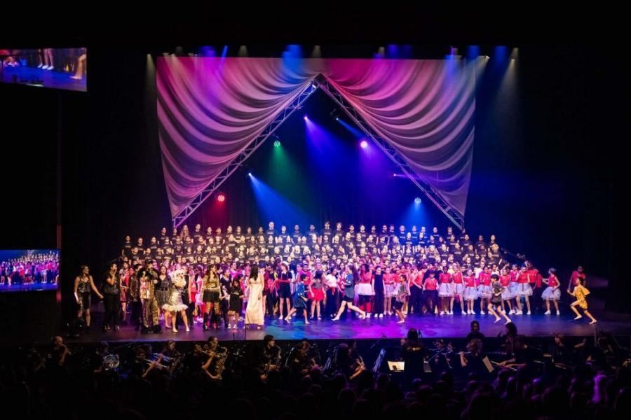 A large group of people are standing on a stage with purple lights
