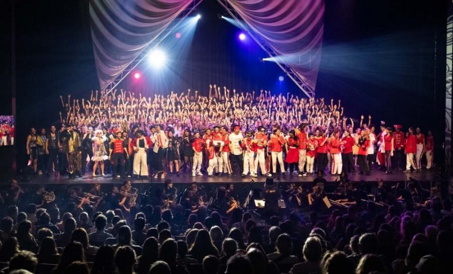 A large group of people are standing on a stage in front of a crowd.