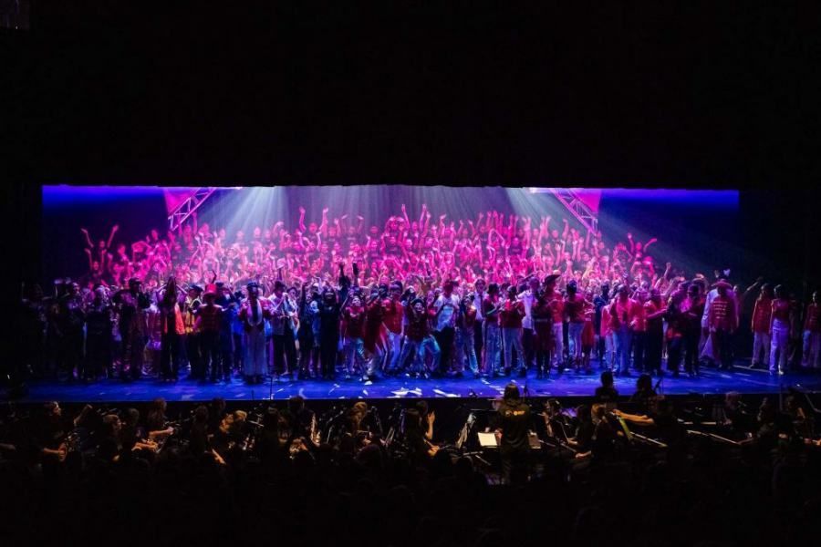 A large group of people are standing on a stage in front of a large screen.