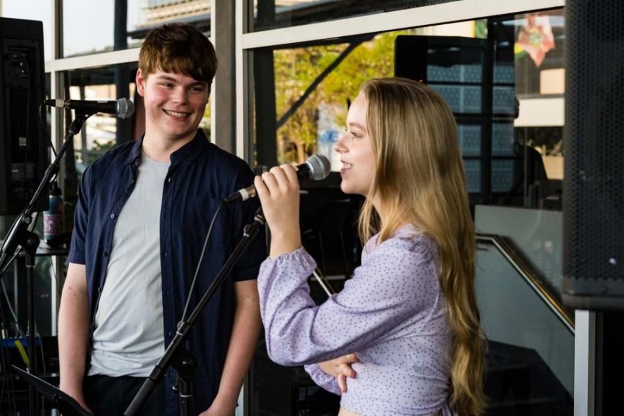 A boy and a girl are singing into microphones.