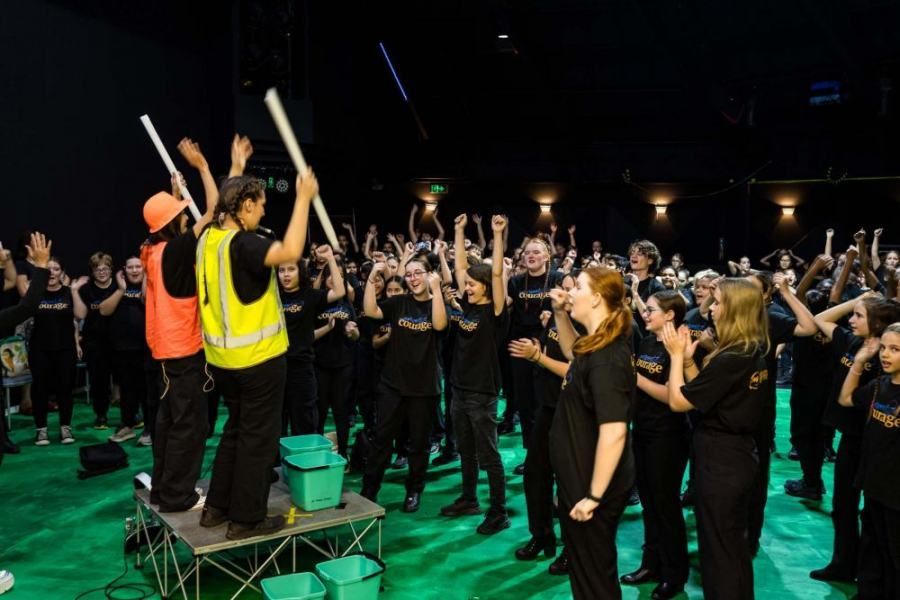 A group of people are standing on a stage with their hands in the air.