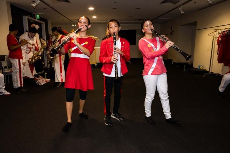 A group of young people are playing clarinets in a room.