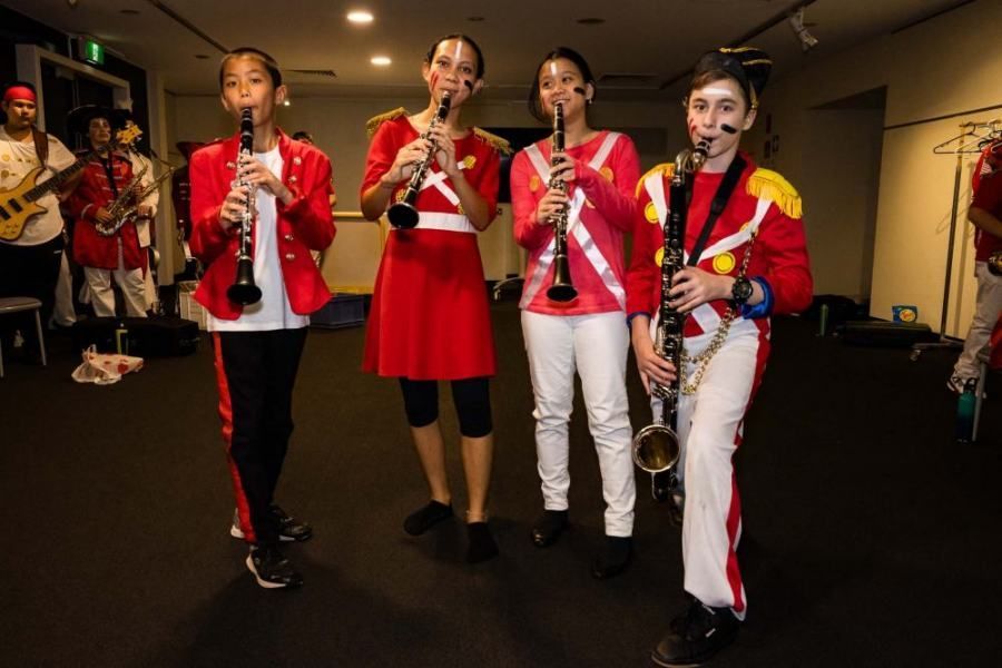 A group of young girls are playing clarinets and saxophones in a band.