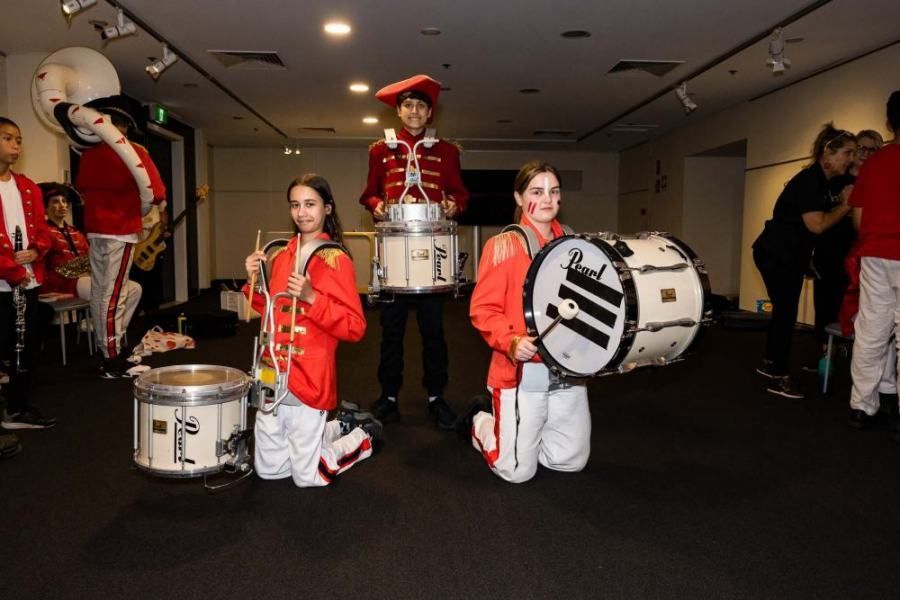 A group of people are kneeling down holding drums in a room.