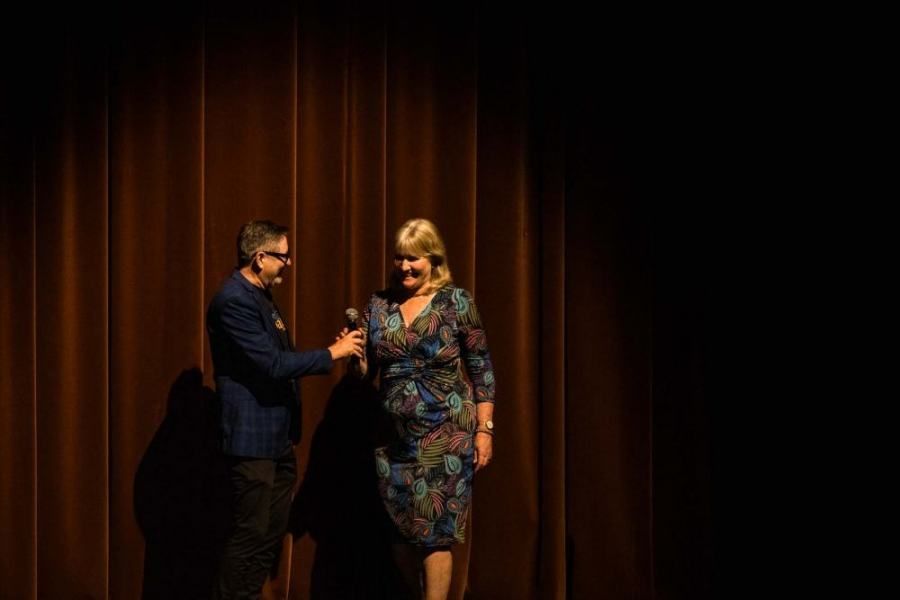 A man is giving a woman a microphone on a stage.