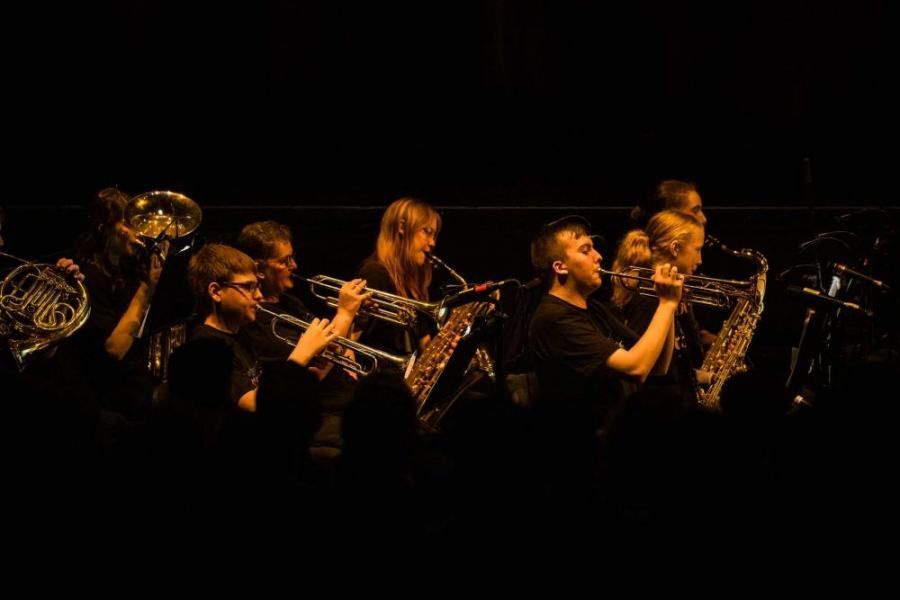 A group of people are playing instruments on a stage in a dark room.