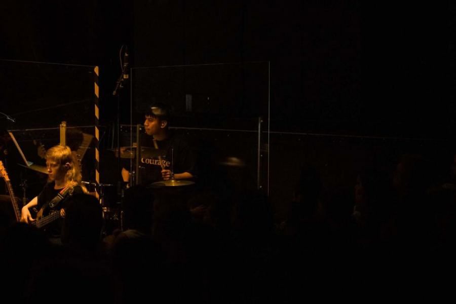 A group of people are playing instruments on a stage in a dark room.