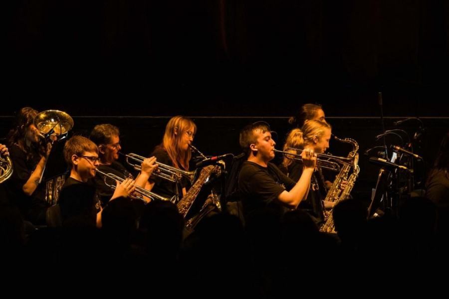 A group of people are playing instruments on a stage in a dark room.