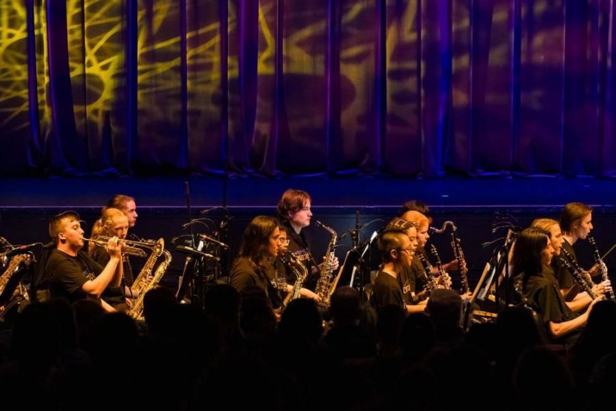 A group of people are playing instruments on a stage in front of a crowd.