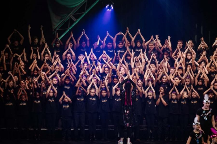 A large group of people are standing on a stage with their hands in the air.