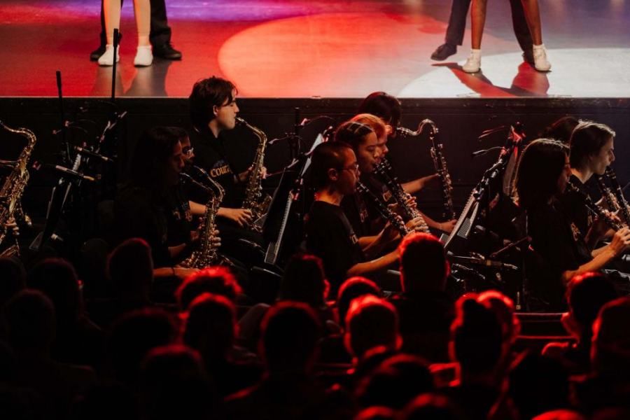 A group of people are playing saxophones on a stage in front of a crowd.