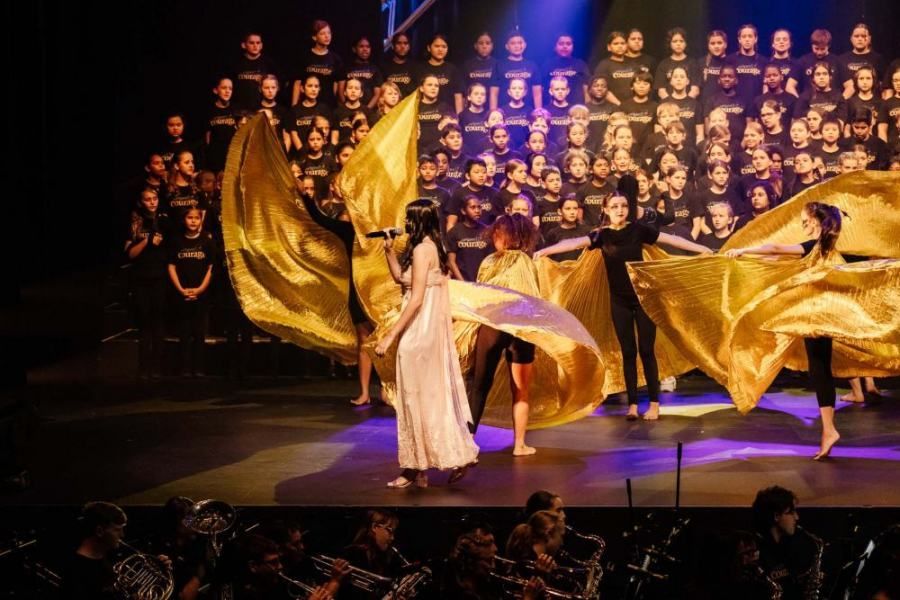 A group of people are dancing on a stage in front of a choir.