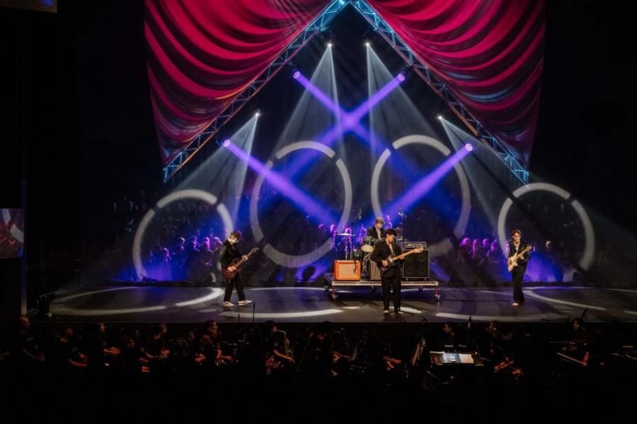 A group of people are playing instruments on a stage in front of a crowd.