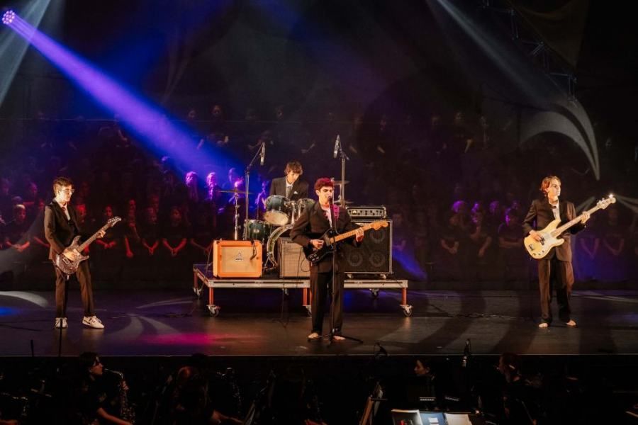 A group of men are playing guitars on a stage in front of a crowd.