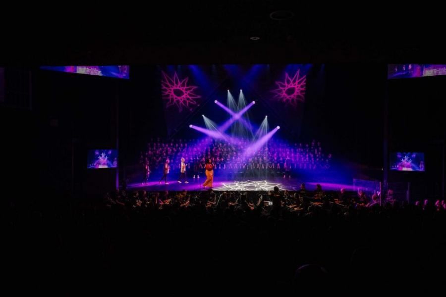 A group of people are standing on a stage with purple lights.