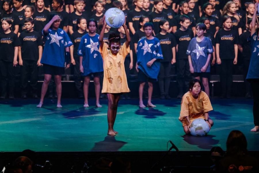 A girl is holding a soccer ball in front of a choir
