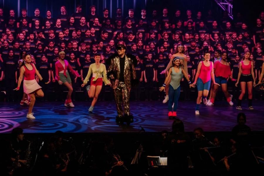 A group of people are dancing on a stage in front of a crowd.