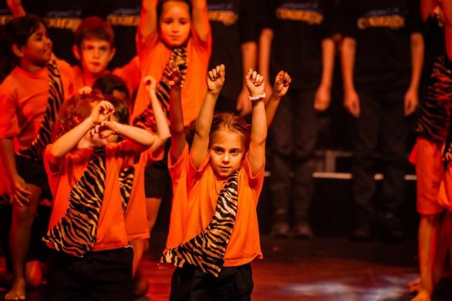 A group of young children are dancing on a stage.