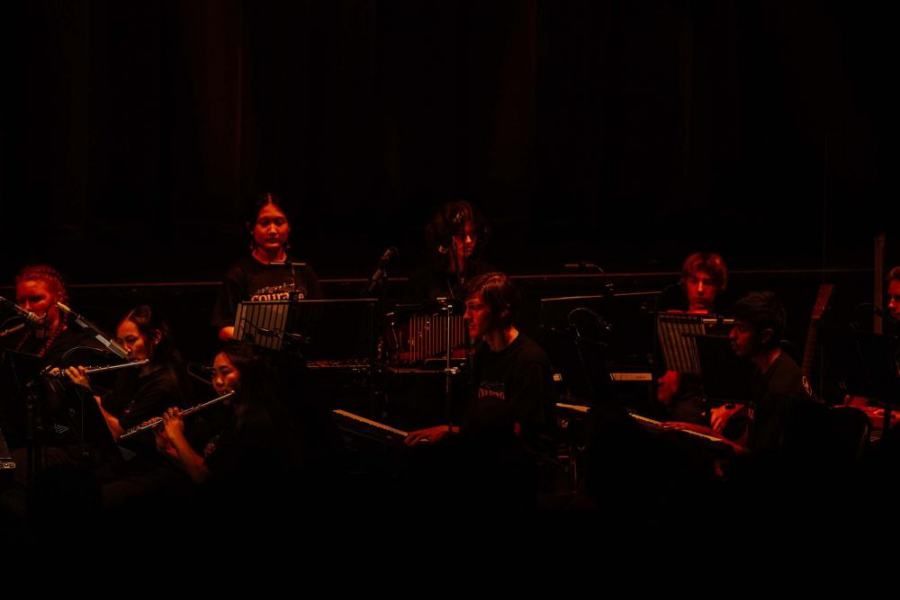 A group of people are playing instruments on a stage in a dark room.