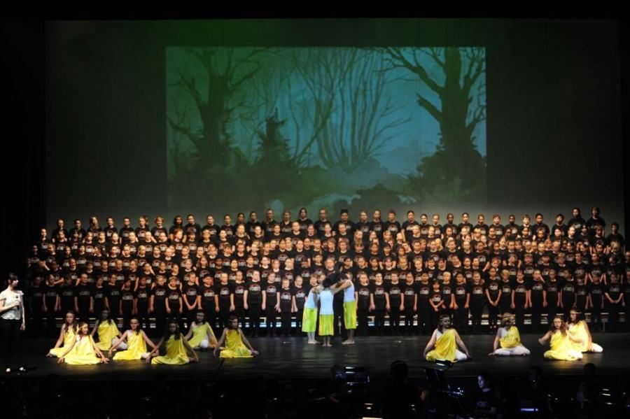A large group of people are on a stage in front of a large screen