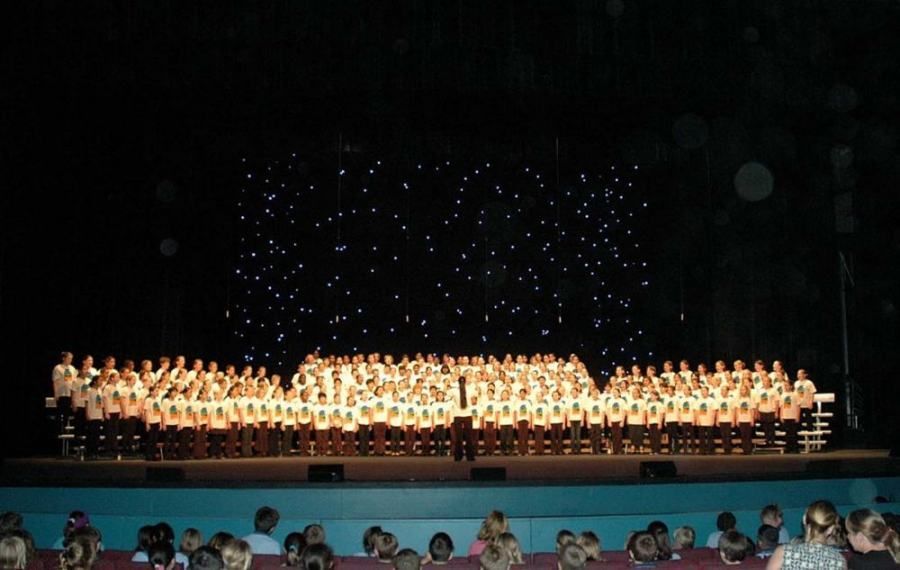 A large choir is performing on a stage at night