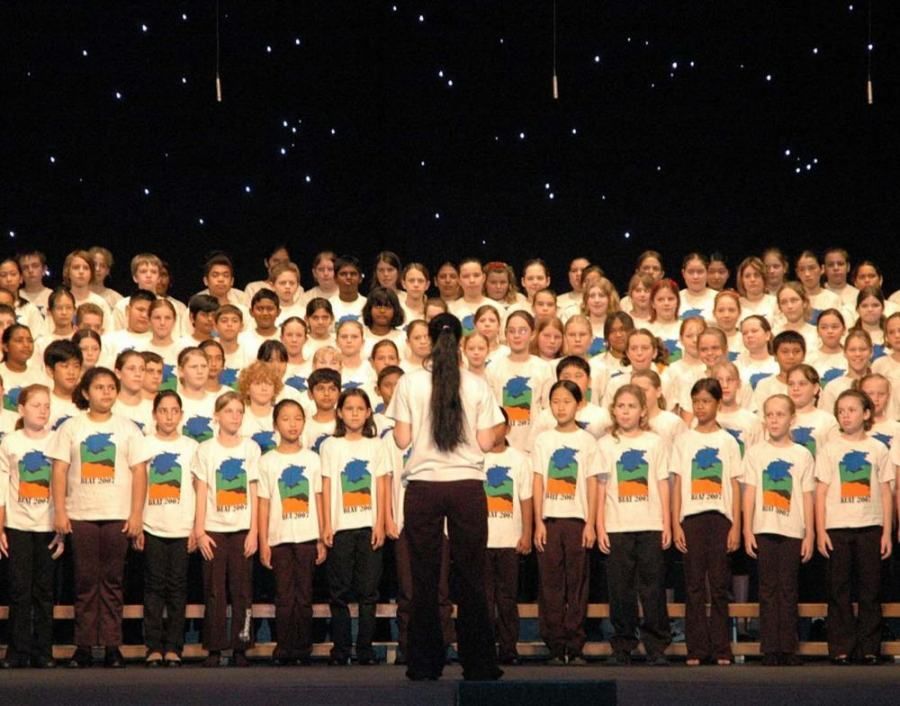 A large group of children are singing in a choir