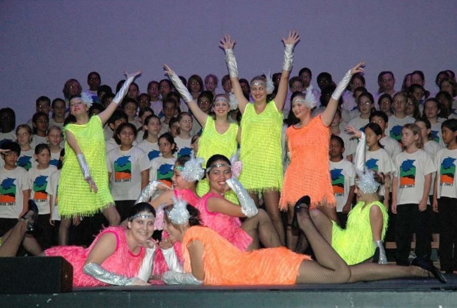 A group of young girls are dancing on a stage in front of a choir.