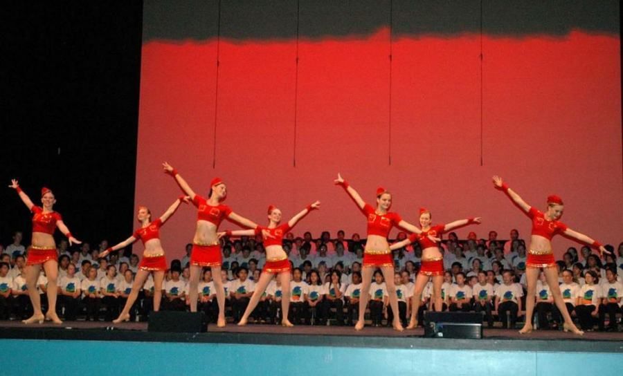 A group of cheerleaders are performing on a stage in front of a crowd