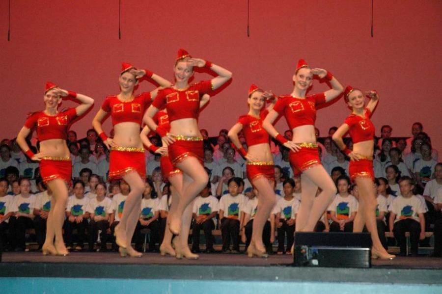 A group of women are dancing on a stage in front of a crowd