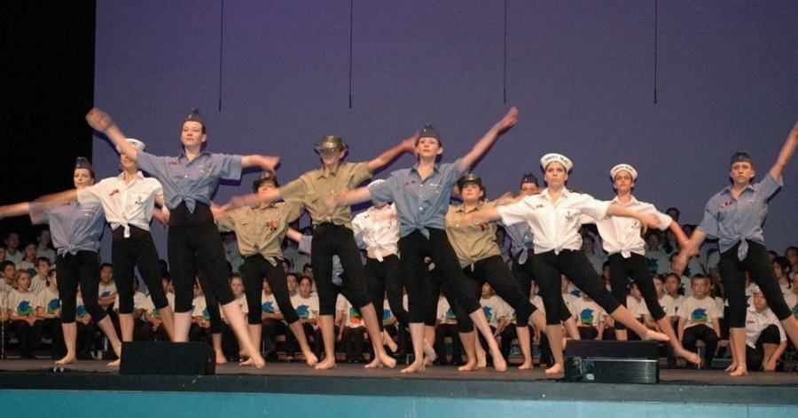 A group of people are dancing on a stage in front of a crowd