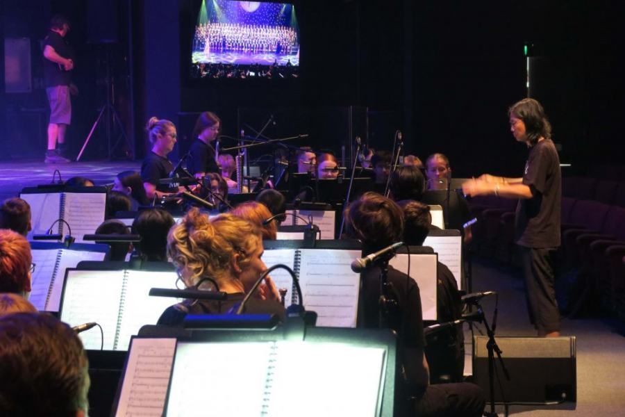 A man is leading an orchestra on a stage