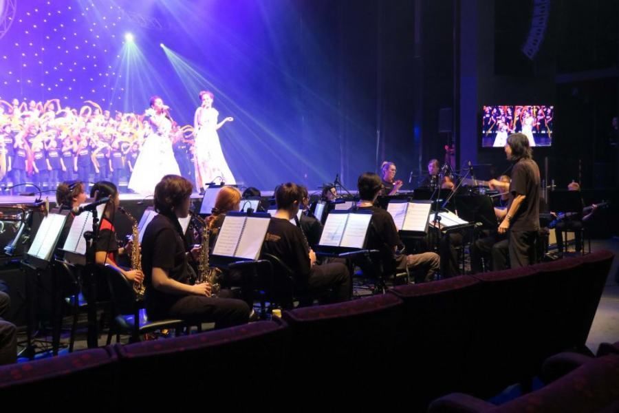 A group of people are sitting in front of an orchestra on a stage.