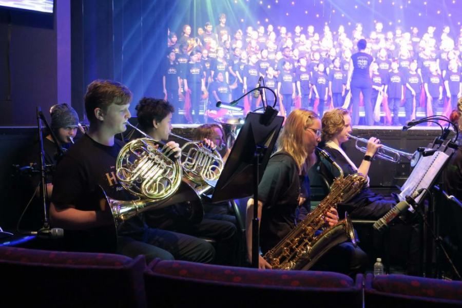 A group of people playing instruments on a stage in front of a choir.