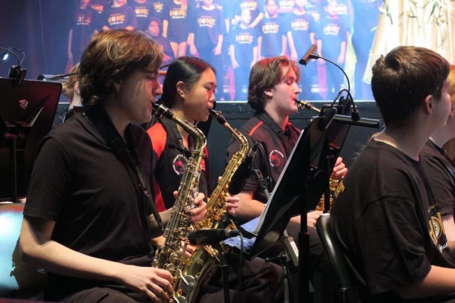 A group of people playing saxophones in front of a choir