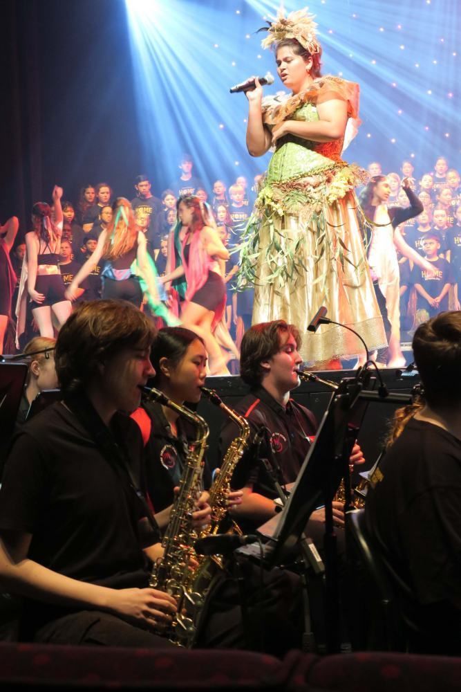 A woman is singing into a microphone while a band plays in the background