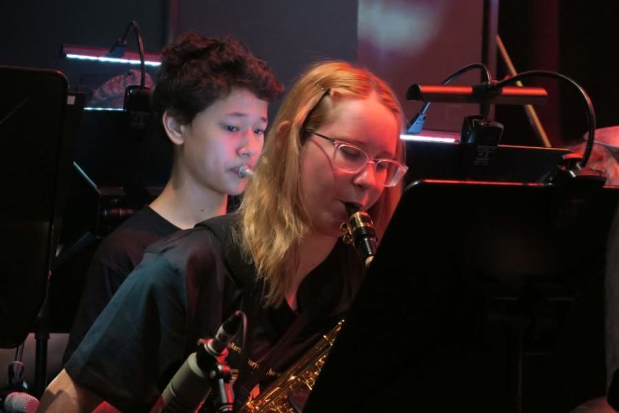 A boy and a girl are playing saxophones in an orchestra