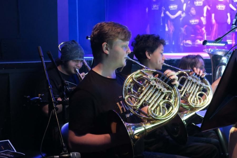 A man is playing a french horn in an orchestra