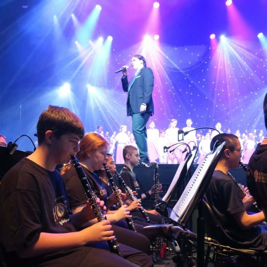 A man singing into a microphone in front of a band