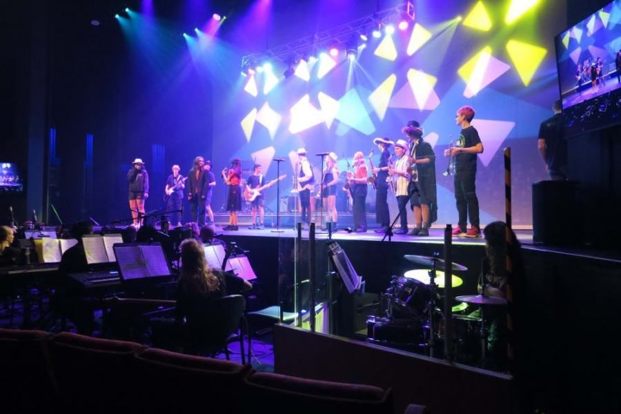 A group of people are standing on a stage in front of a crowd.