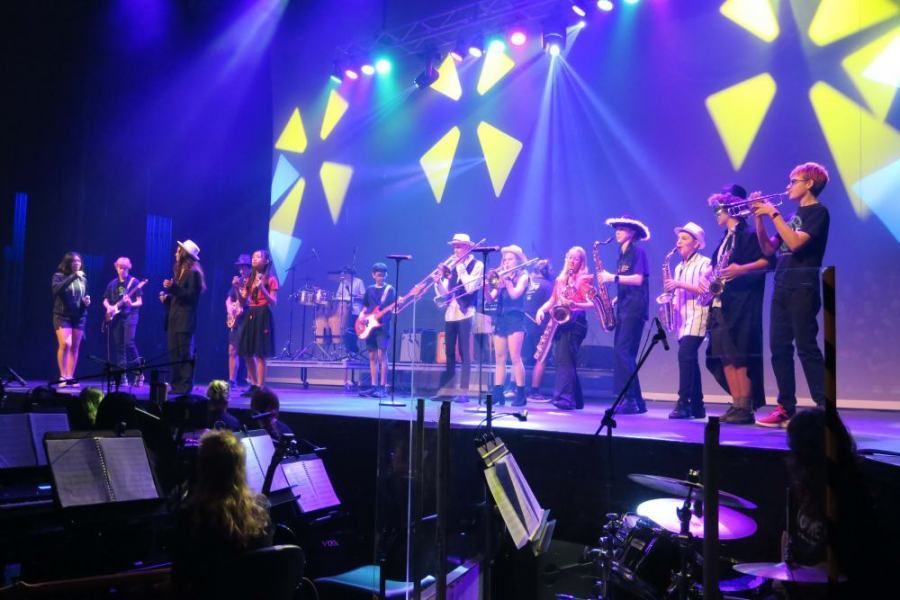 A group of people are standing on a stage playing instruments.