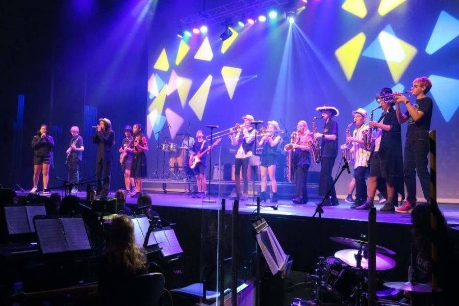 A group of people are standing on a stage playing instruments.