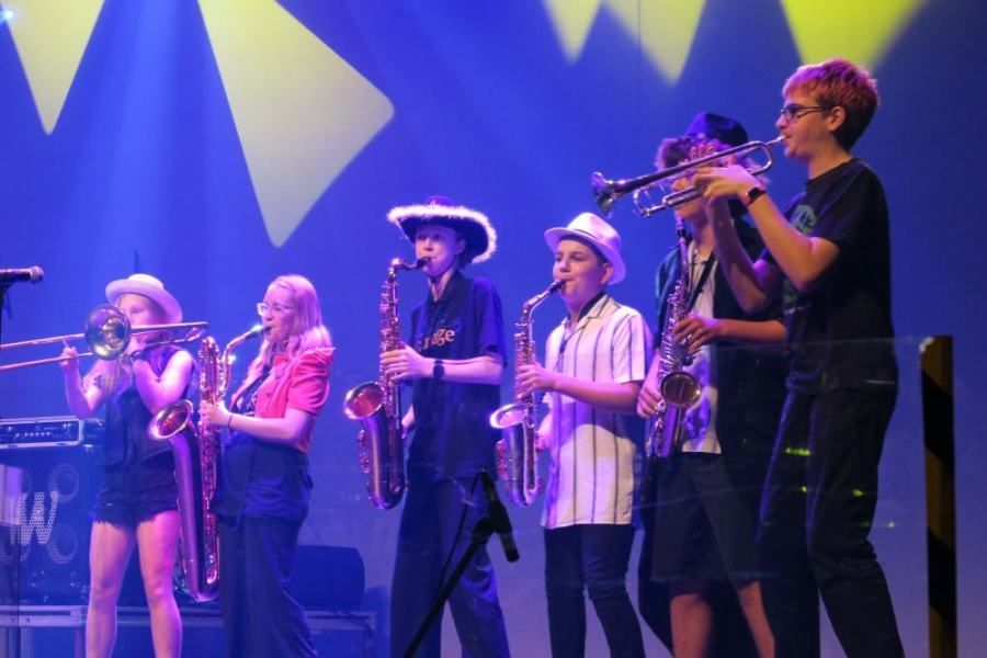 A group of young people are playing instruments on a stage