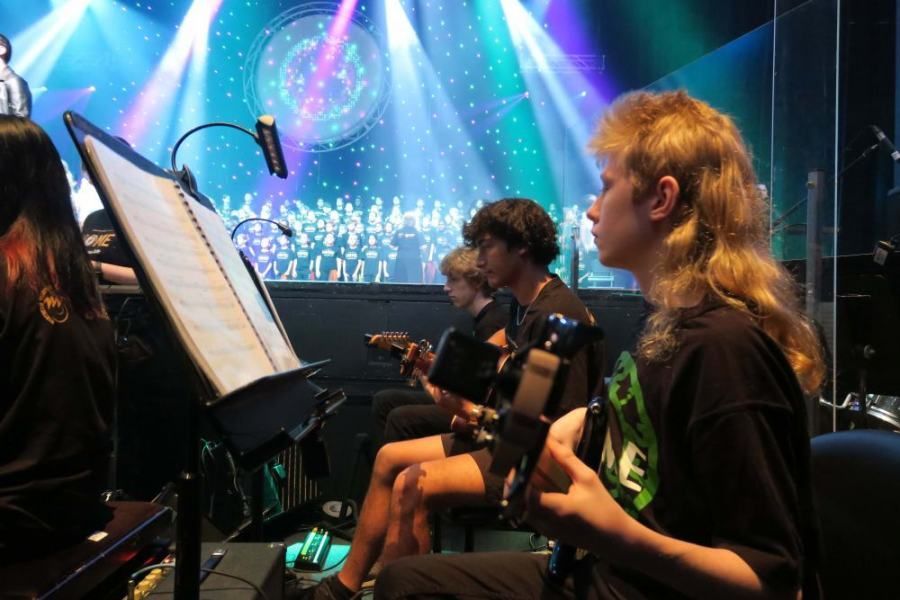 A group of young people are playing musical instruments on a stage.