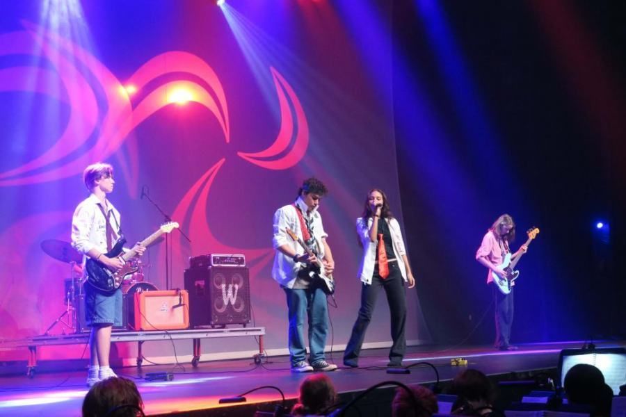 A group of people playing instruments on a stage with the letter w behind them
