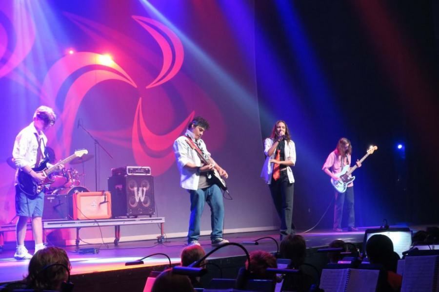 A group of people playing instruments on a stage with the letter w in the background