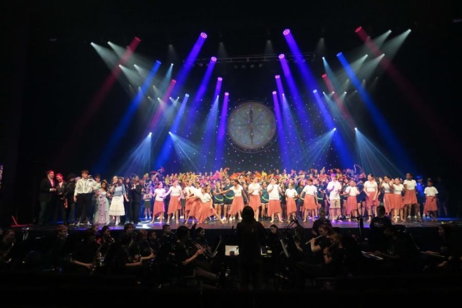 A large group of people are standing on a stage in front of a crowd