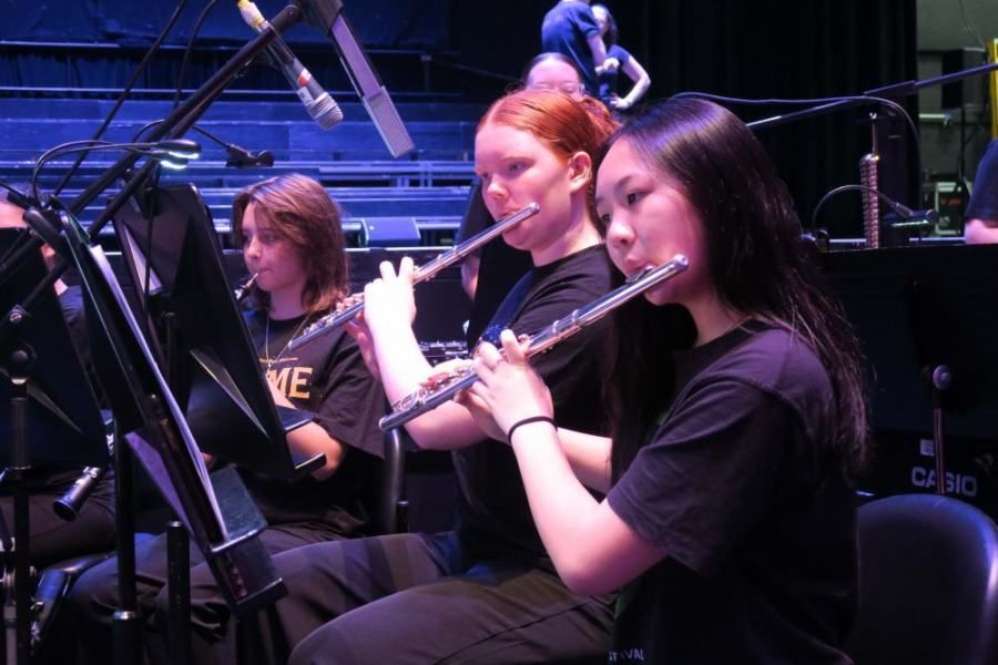 A group of young girls are playing flutes in an orchestra