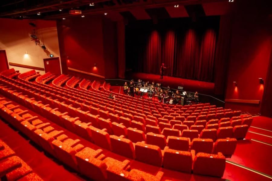 An empty theater with red seats and a band on stage