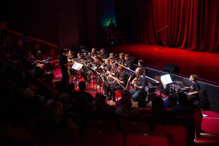 A large orchestra is playing on a stage in front of a crowd.